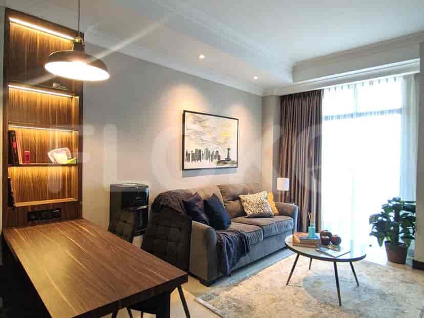 A well-lit living room featuring a sofa, side table, bookshelf, and large window.