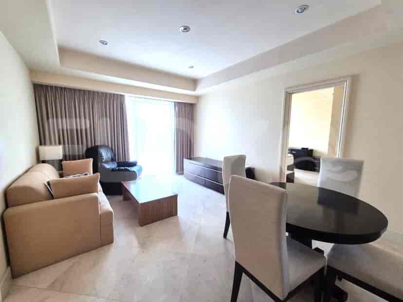 Ruang tamu dengan sofa, kursi lengan, meja makan, dan rak TV.