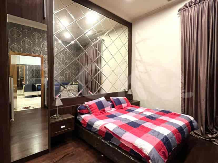 Bedroom with a bed, a mirror wall, and a dark wood closet.