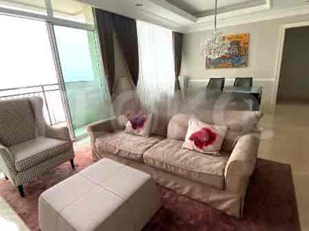 Ruang tamu yang terang benderang dengan sofa krem, area makan, dan pemandangan kota.