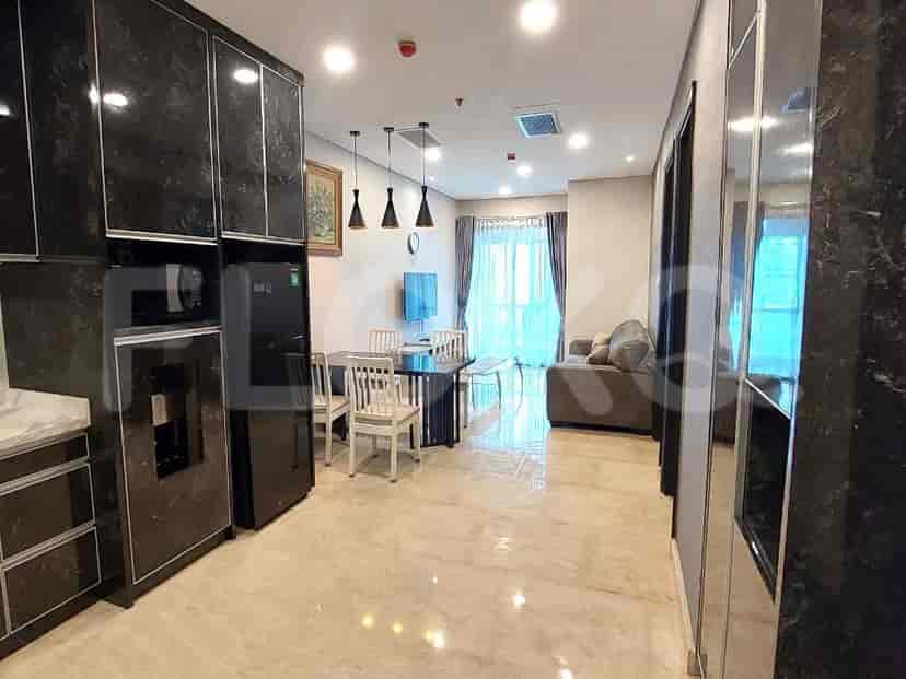 Modern kitchen with black cabinetry, a dining table, and an adjacent living area visible.