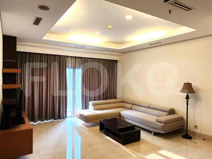 Ruang tamu dengan sofa berbentuk L berwarna abu-abu, TV, dan jendela besar.