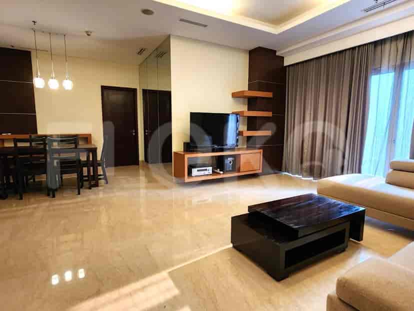 Area gabungan ruang tamu dan ruang makan dengan meja makan, TV, dan akses ke area makan.