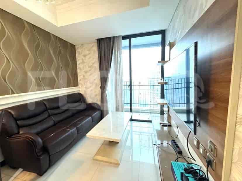 Modern living room with leather sofa, TV, and large window.