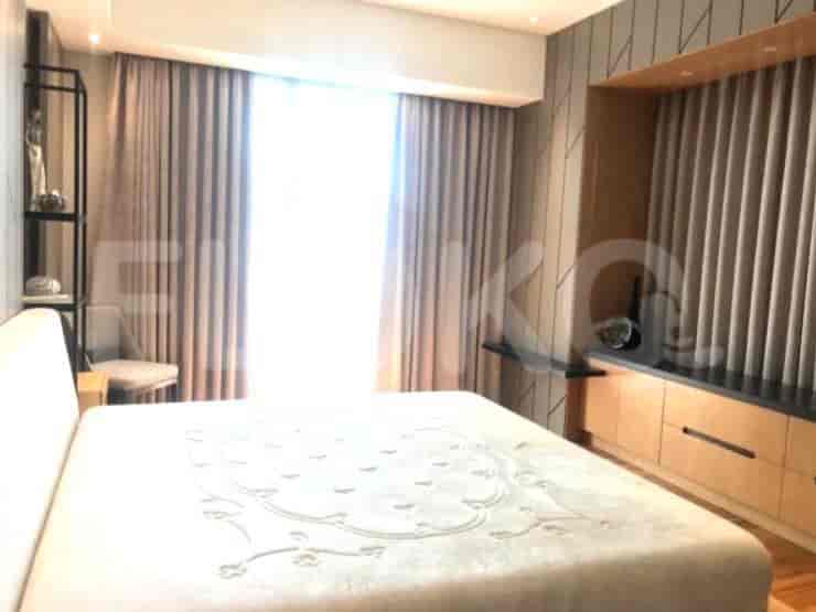 A bedroom with a bed and a large window with curtains.