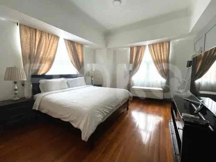 Bedroom with a bed, nightstands, and large windows.