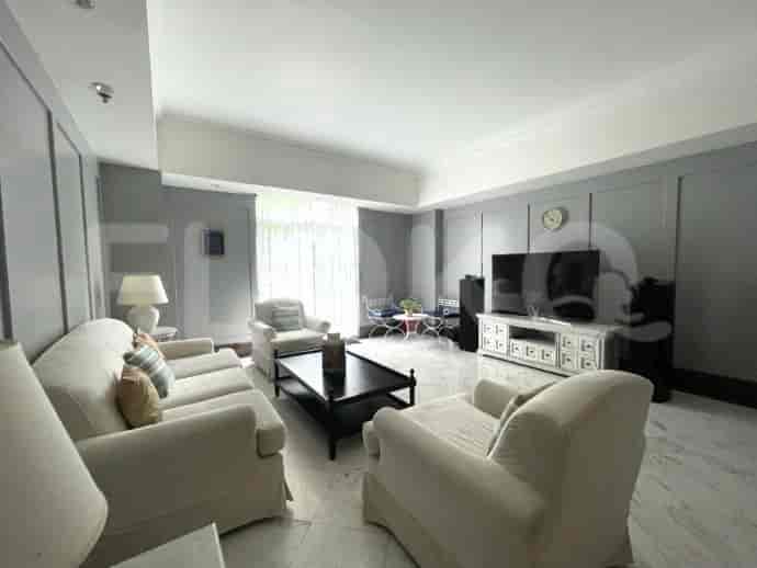 Spacious living room with white couches, a TV, and large windows.