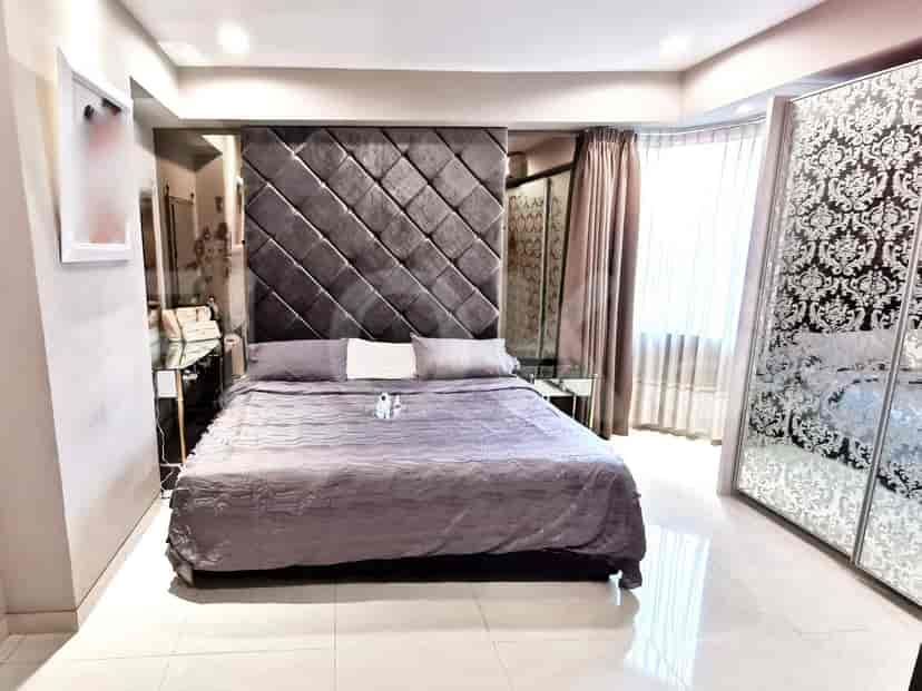 A modern bedroom with a large bed, cushioned headboard, and a mirrored sliding closet.