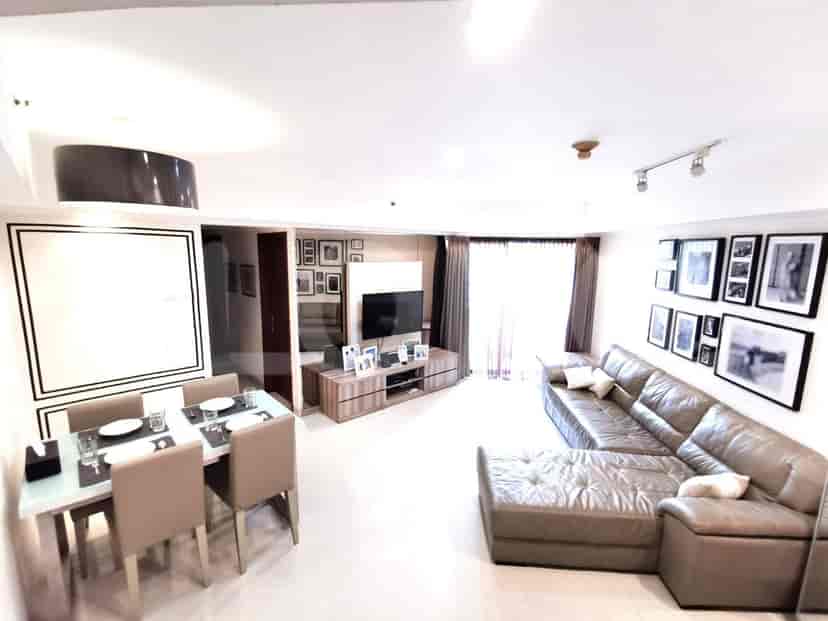 A spacious living room with an L-shaped grey sofa, wall-mounted smart TV, and dining area.