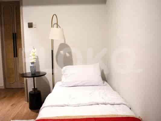 Kamar tidur minimalis dengan tempat tidur tunggal, meja samping tempat tidur, dan lampu tinggi.