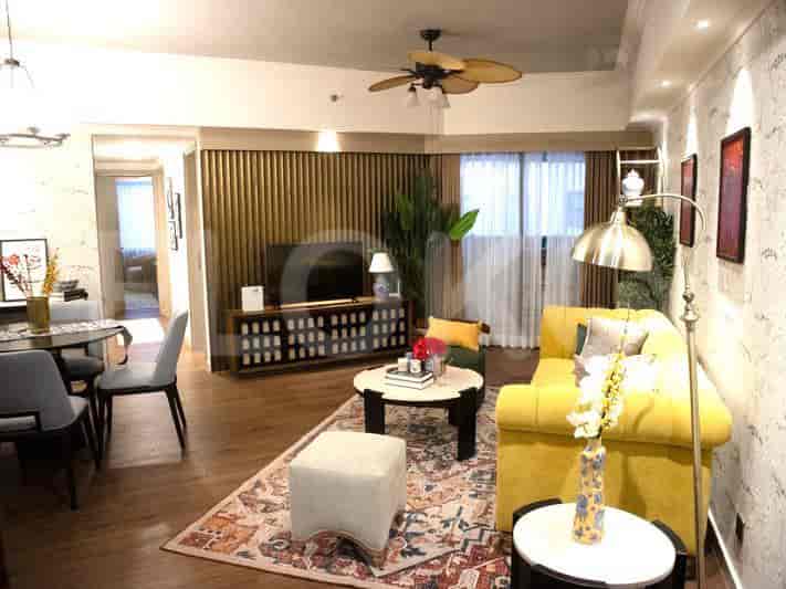 Ruang tamu yang luas dengan sofa kuning, karpet bermotif, dan aksen kayu.