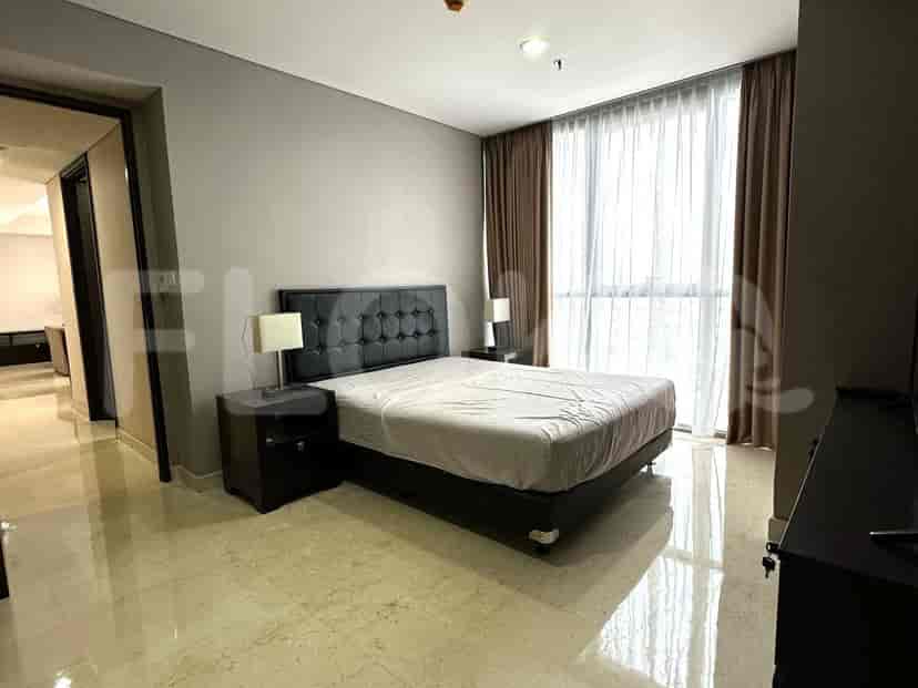 A bedroom with a bed, nightstands, and a large window.