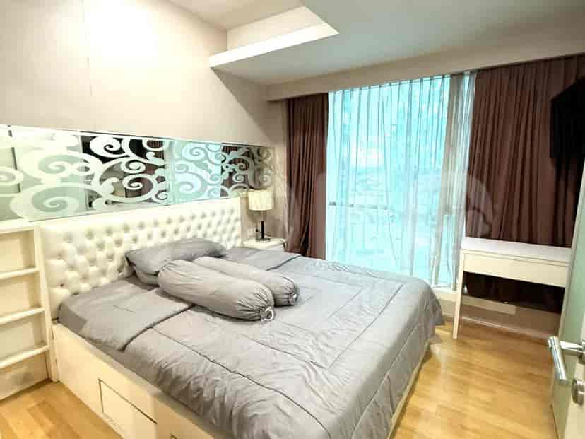 A bedroom with a bed and a large window.