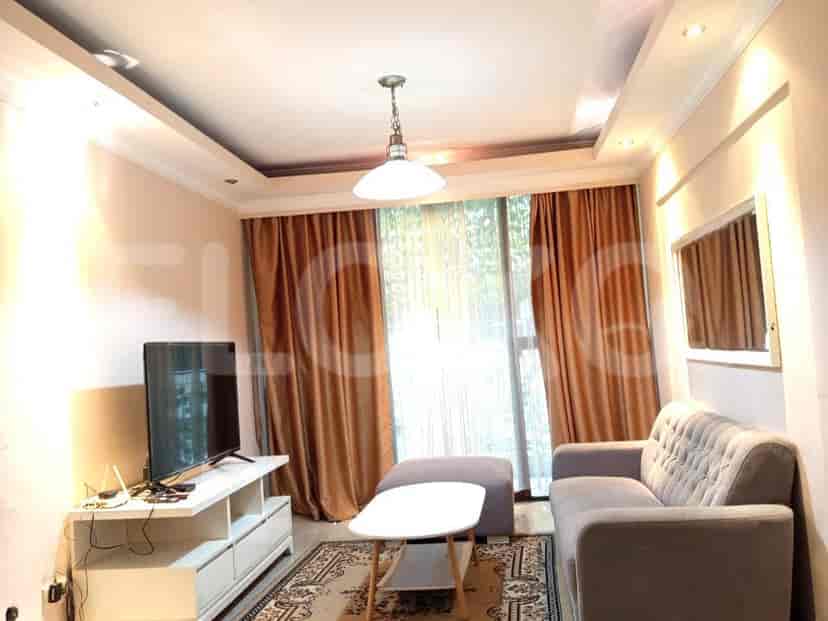 Living room with a TV, sofa, and large windows with curtains.