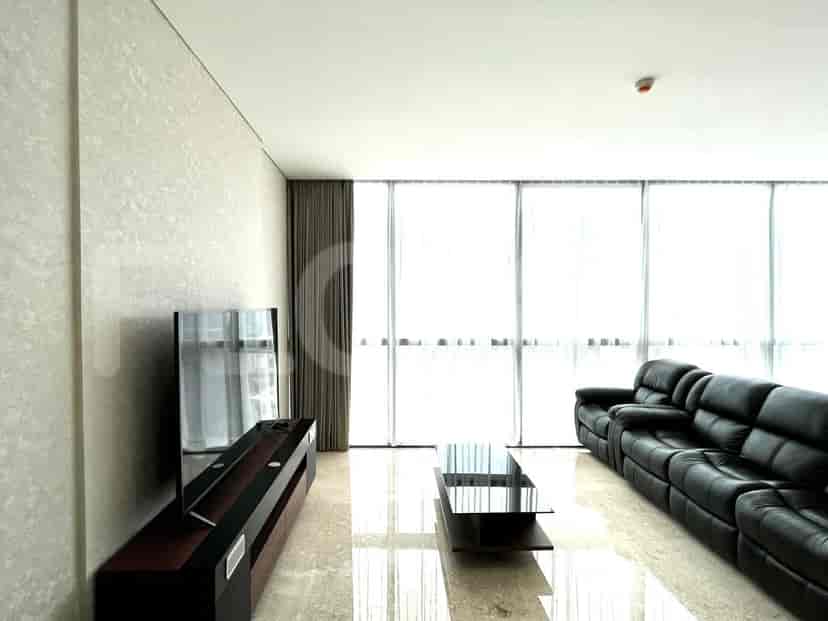 Modern living room with a black leather sofa, TV, and glass table.