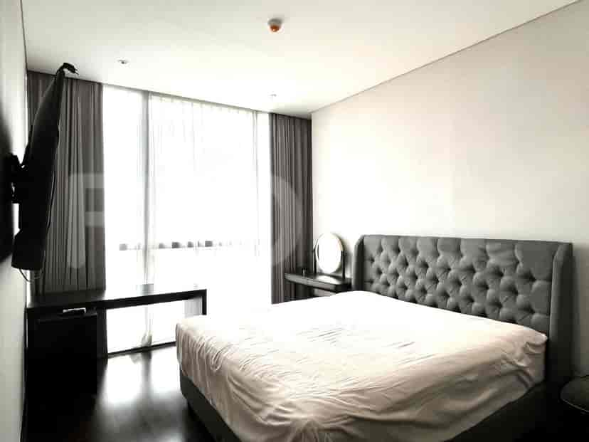 Bedroom featuring a large bed, large window, and mounted TV.