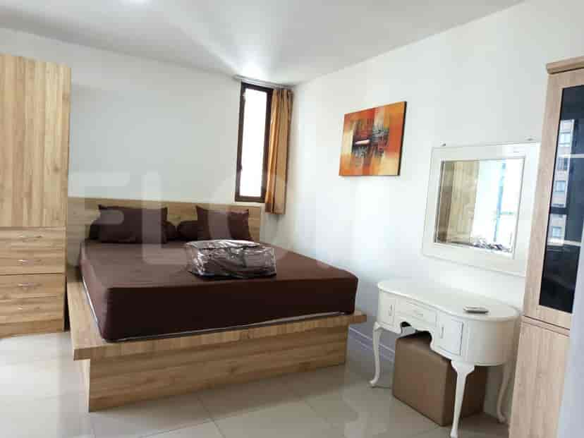 Bedroom with a wooden bed frame, matching wardrobes, and a small vanity table.
