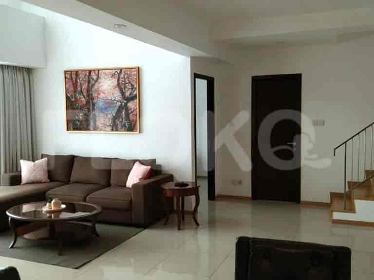 A living room with a brown sofa, round coffee table, and artwork.