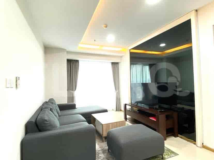 Modern living room with grey sectional sofa, TV, and large windows.