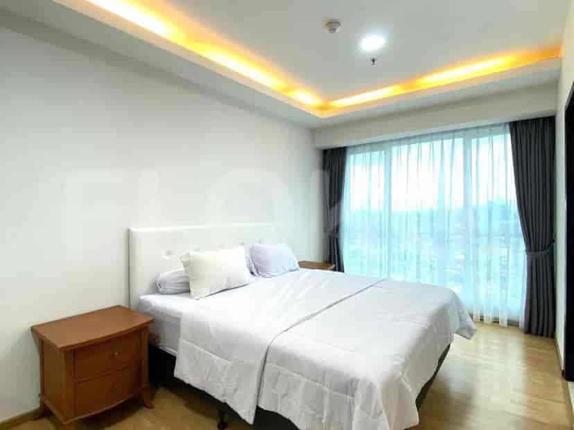Bedroom with a king-size bed, bedside table, and large windows.