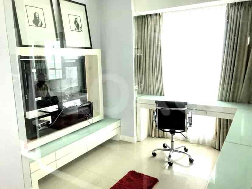 An entertainment area with a TV, desk, and large windows.