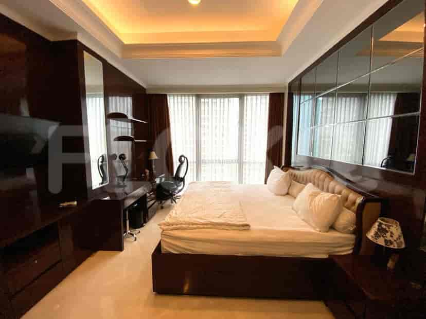 Luxurious bedroom with a large bed, desk, and mirrored wall.