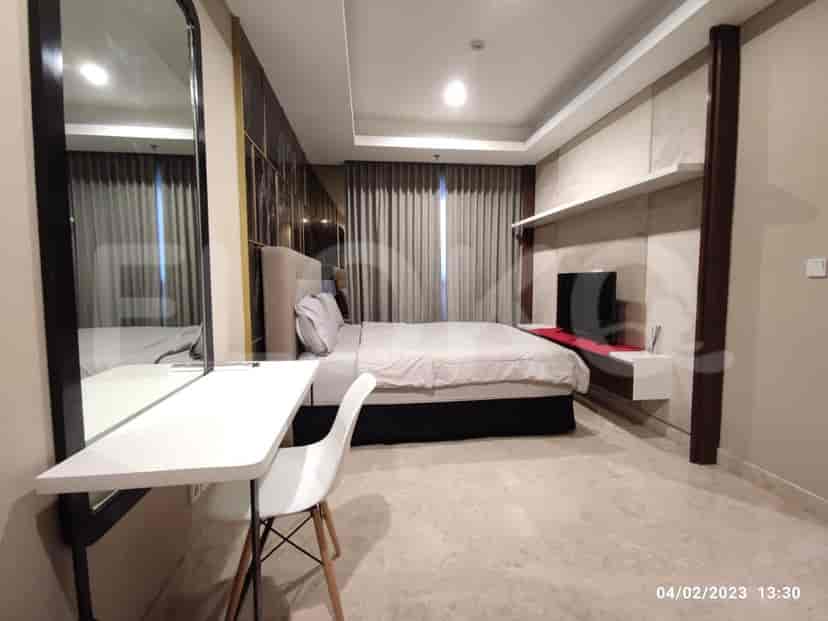 A well-lit bedroom with a large bed, mirror, and a desk.