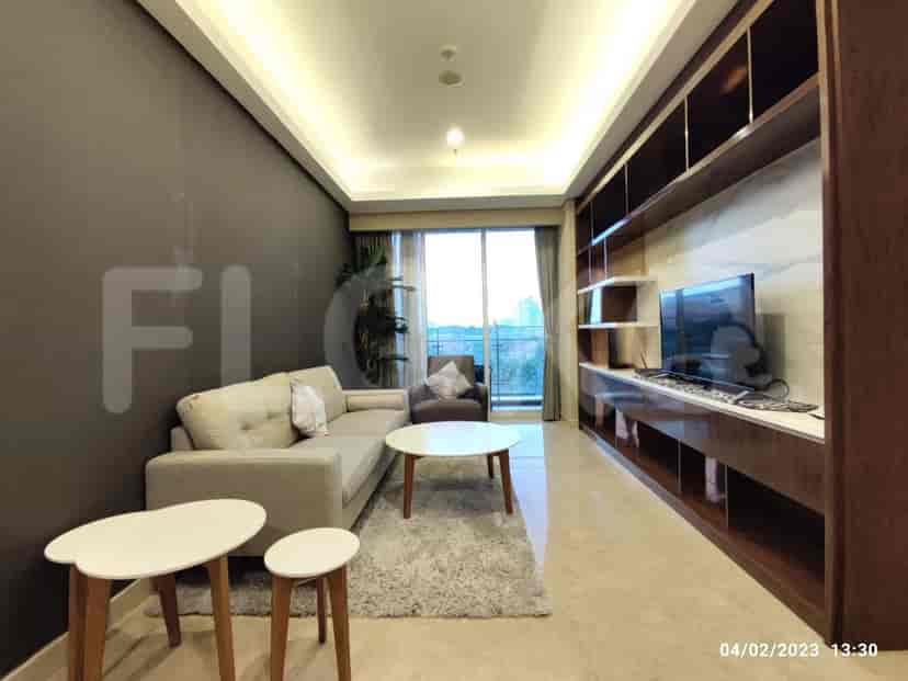A modern living room with a grey sofa, built-in shelving, and a view through large windows.