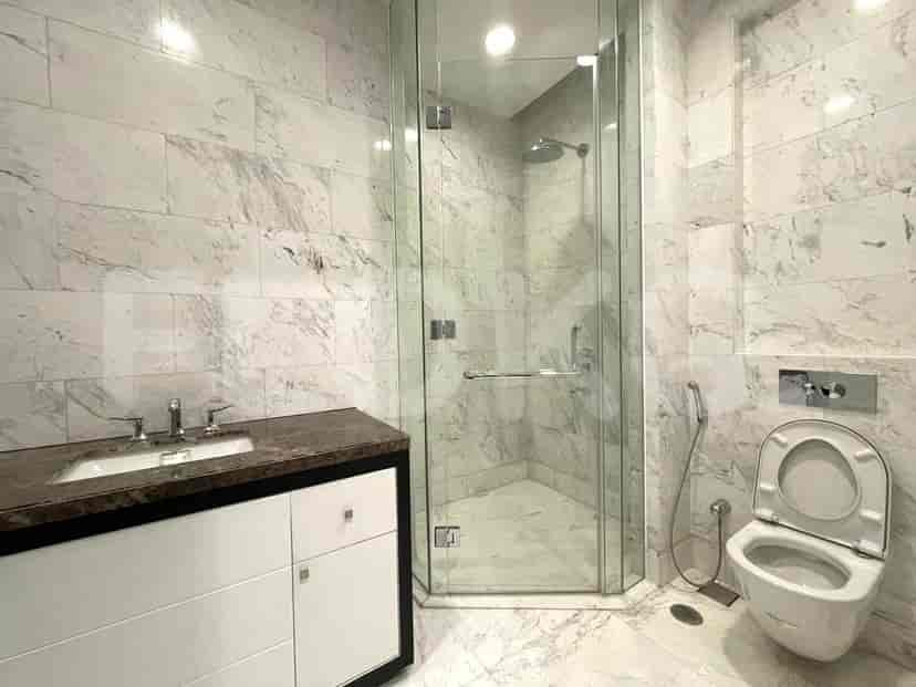 A modern bathroom with marble walls and flooring, featuring a glass shower and a vanity.
