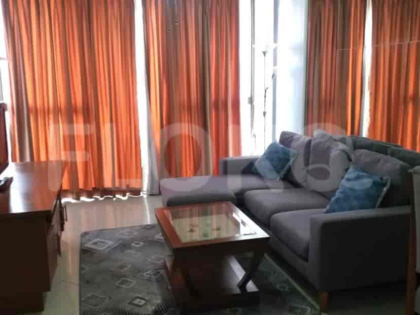 Living room with an L-shaped sofa, wooden furniture, and large windows.