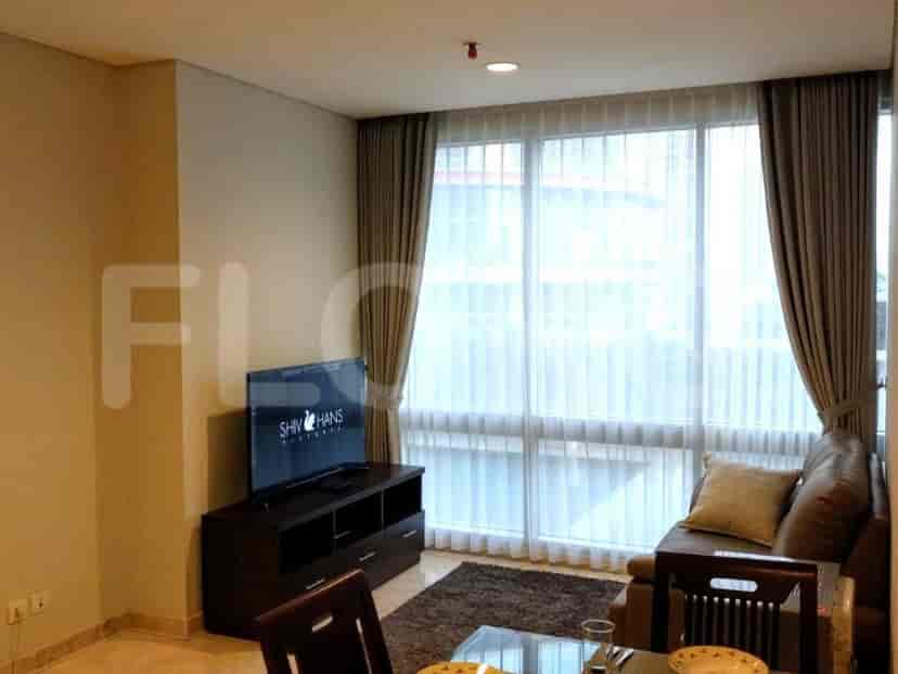 A living room with a TV, sofa, and large windows.
