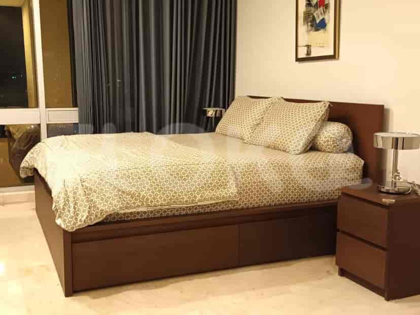 A bedroom with a bed, nightstands and curtains.