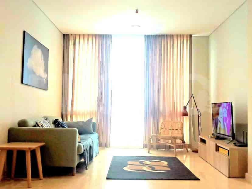 A spacious living room with a grey sofa, smart TV, and large window.