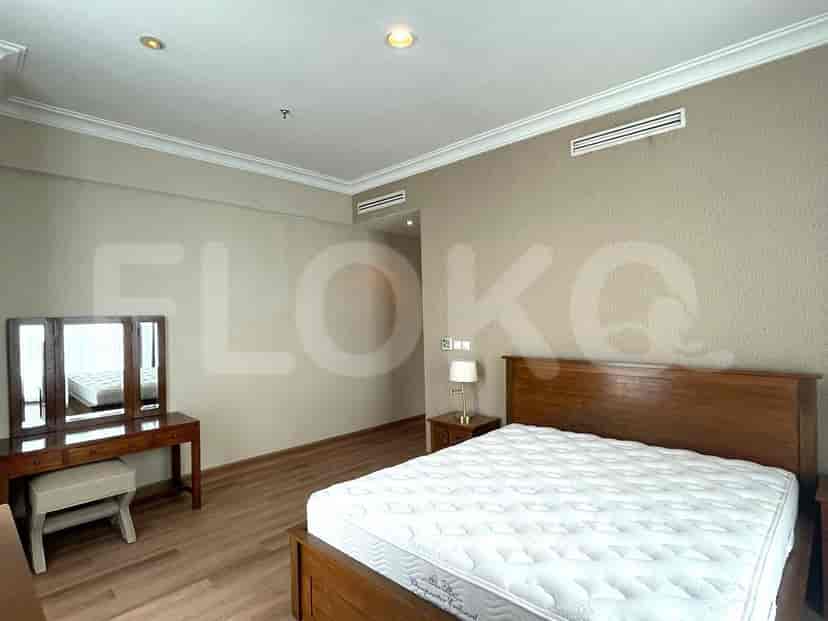 A well-lit bedroom featuring a bed, vanity, and light-colored walls.