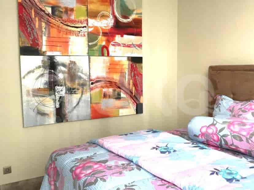A bedroom with a bed, artwork, and bedspread.