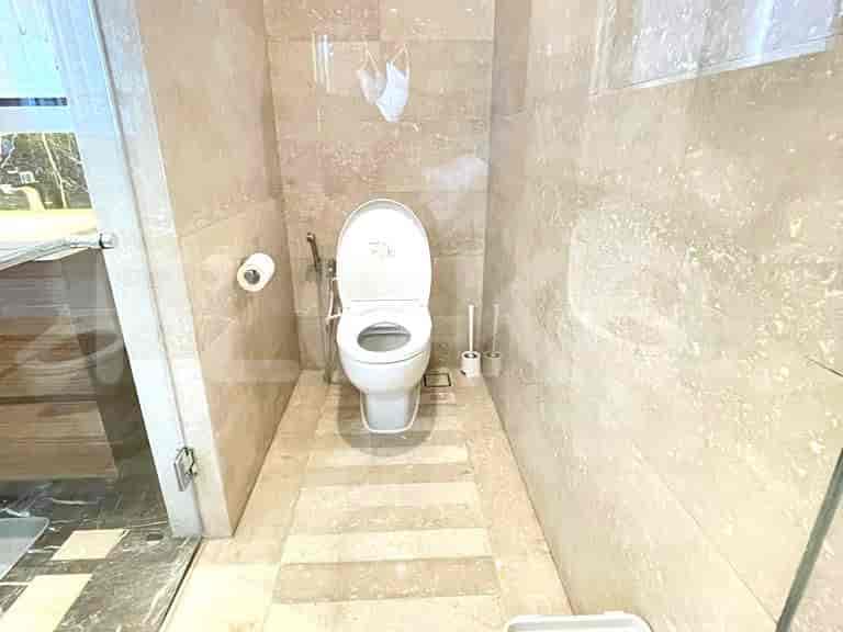 Bathroom featuring a toilet, beige tile walls, and a glass shower enclosure.