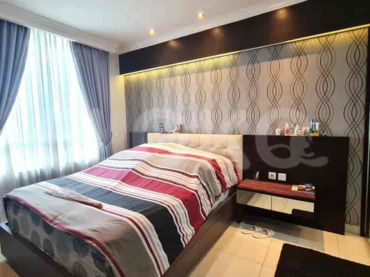 Kamar tidur dengan tempat tidur besar, seprai bermotif, dan meja samping tempat tidur.