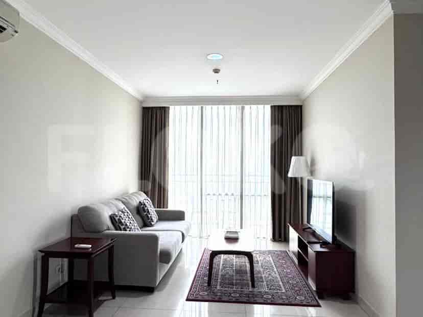 A modern living room with a grey sofa, a mounted TV, and a large window.