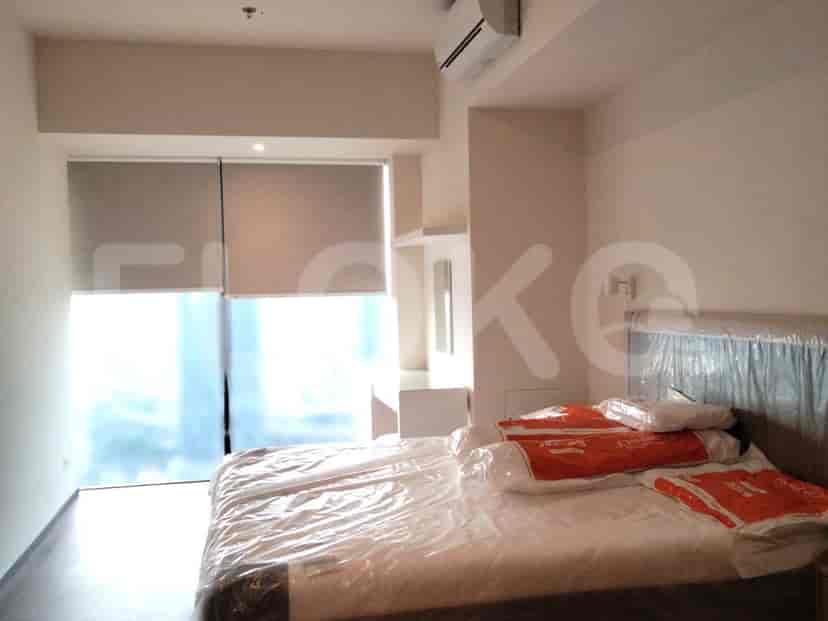 A bedroom with a bed covered in plastic and a large window.
