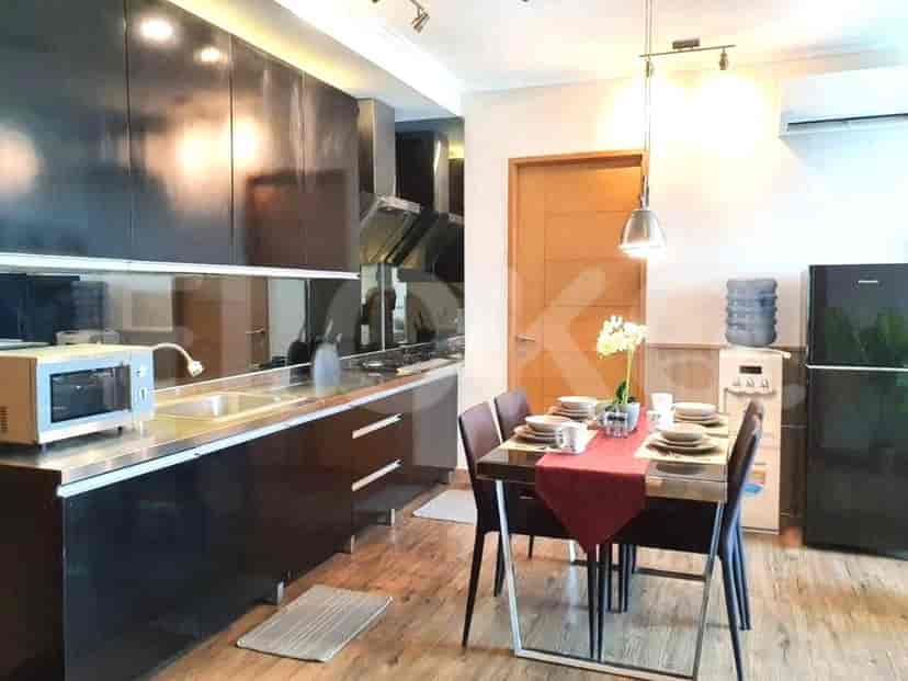 A modern kitchen and dining area with sleek black cabinetry, stainless steel appliances, and a dining table for four.