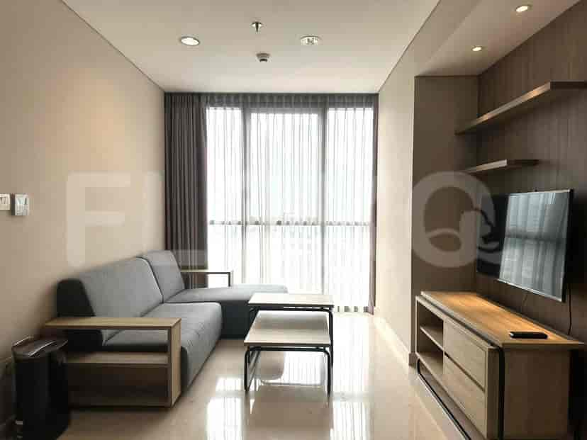 Modern living room with grey sofa, TV, and large window.