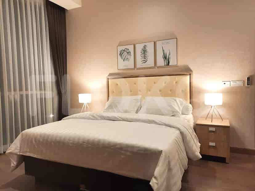 A well-lit bedroom with a double bed, bedside tables and wall art.