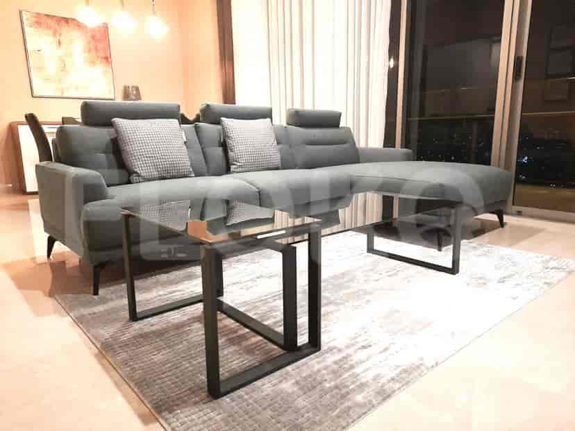 A modern living room featuring a gray sectional sofa and a glass coffee table.