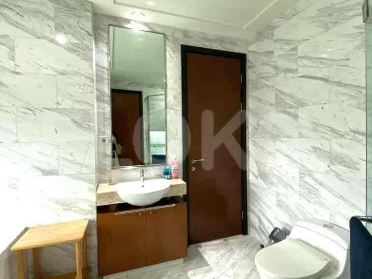 Kamar mandi modern dengan dinding marmer, wastafel, dan toilet.