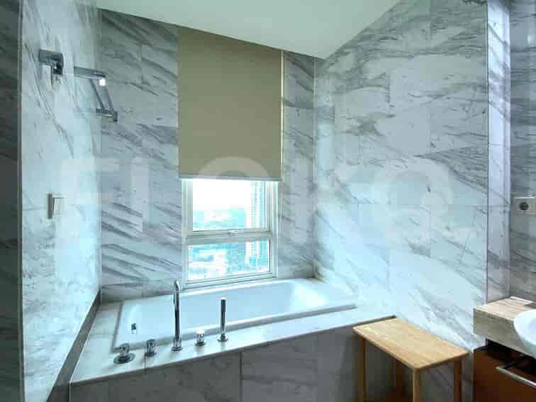 Kamar mandi dengan dinding marmer, bak mandi, dan jendela.