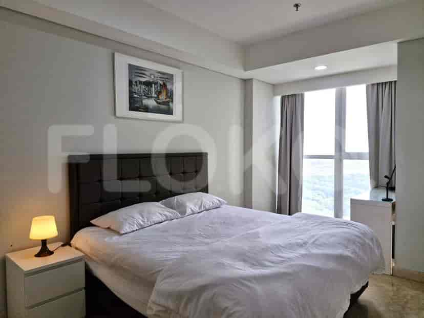 A bedroom with a double bed, bedside table, and a window.