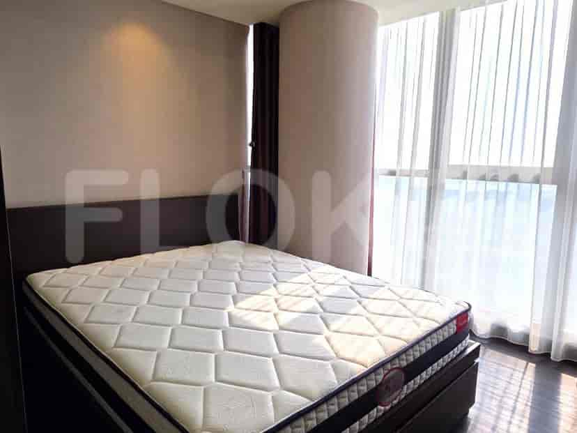 A bedroom featuring a large bed with white linens and sheer curtains.
