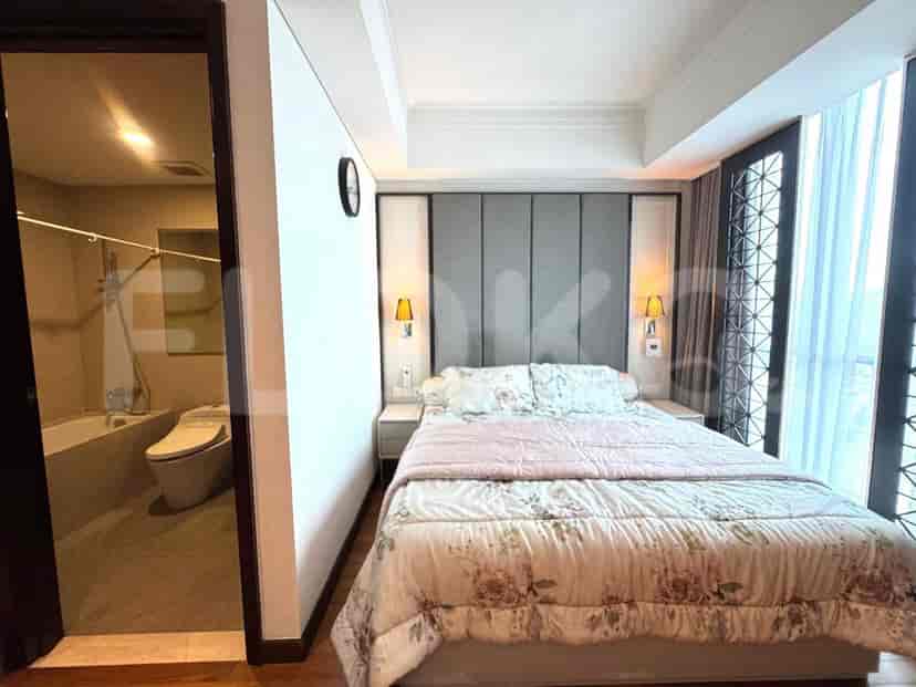 A well-lit bedroom featuring a bed with a floral patterned comforter, and a doorway to the bathroom.
