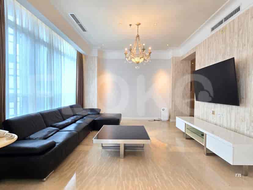 A luxurious living room with a black L-shaped sofa, a large TV, and a chandelier.