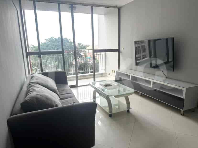 A living room with a grey sofa, TV, and a glass-top coffee table.